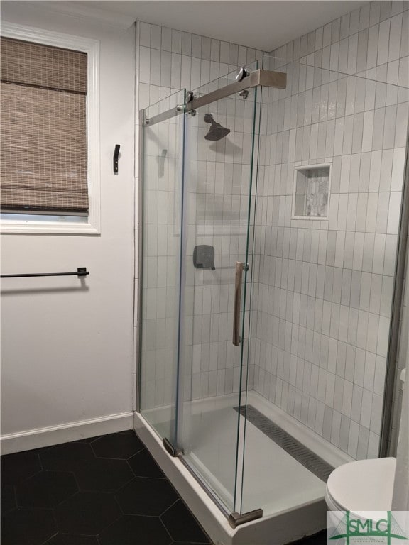 bathroom with toilet, walk in shower, and tile patterned flooring