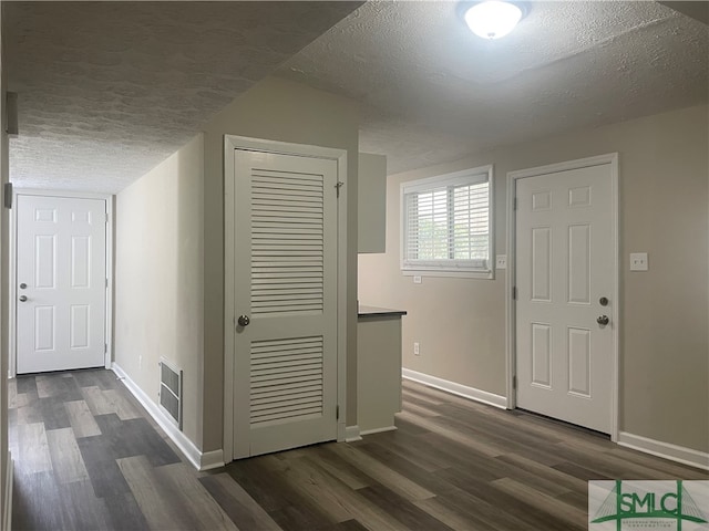 hall featuring dark wood-type flooring and a textured ceiling