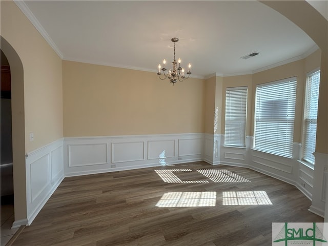 spare room with a notable chandelier, ornamental molding, and dark wood-type flooring