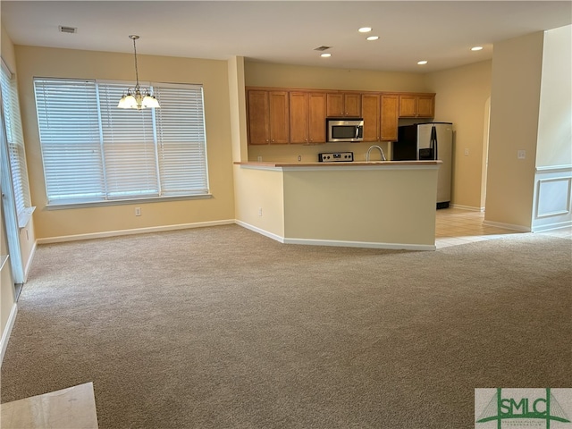 kitchen featuring a chandelier, appliances with stainless steel finishes, light carpet, and pendant lighting