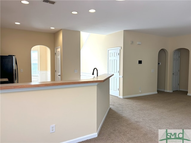 kitchen featuring light carpet, stainless steel refrigerator, and sink