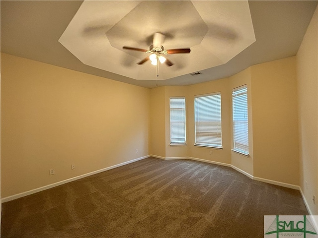 empty room featuring carpet flooring, a tray ceiling, and ceiling fan