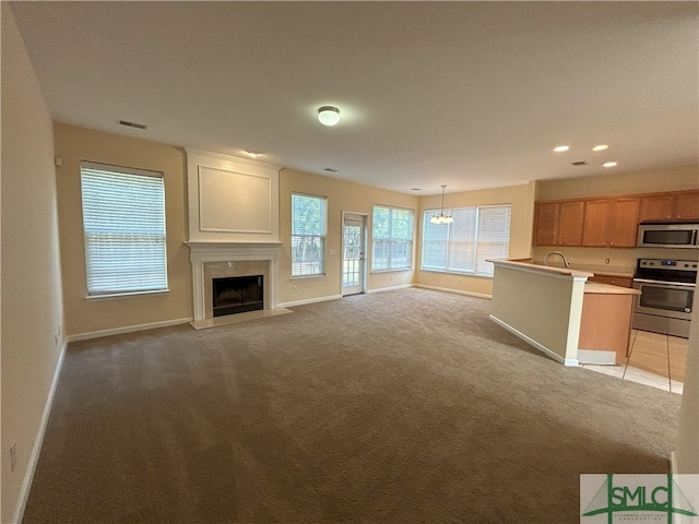 unfurnished living room with a notable chandelier, sink, light carpet, and a fireplace