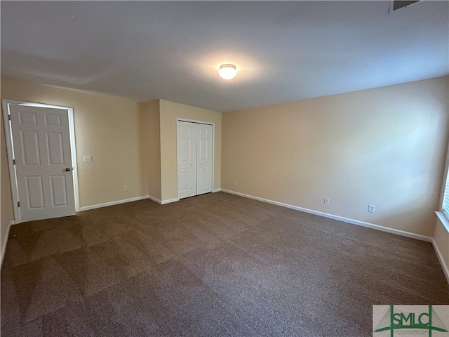 unfurnished bedroom featuring dark colored carpet and a closet