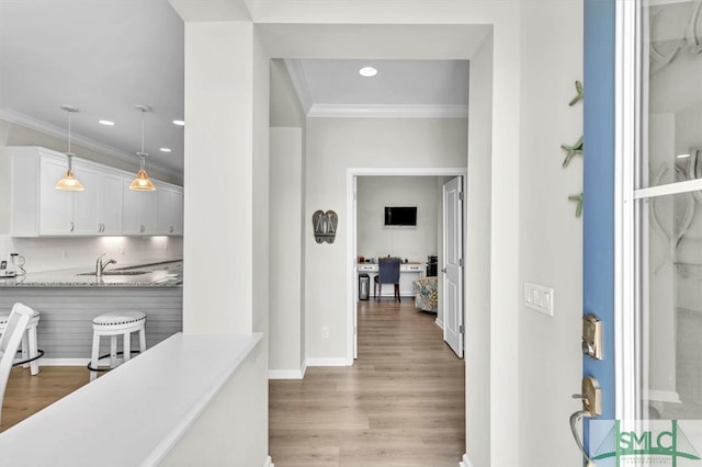 hallway featuring ornamental molding, sink, and light hardwood / wood-style flooring