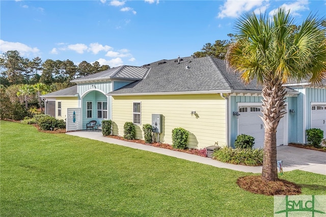 back of property with a garage and a lawn