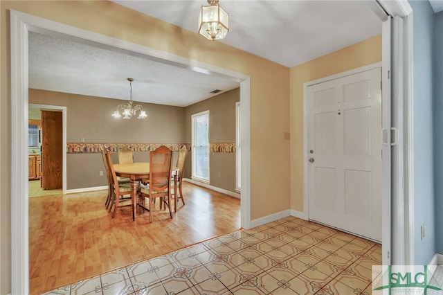 dining space featuring a textured ceiling, an inviting chandelier, and light wood-type flooring