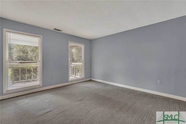 carpeted empty room with a textured ceiling