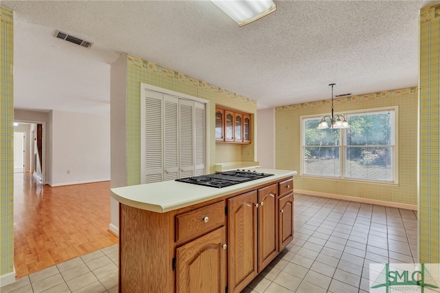 kitchen with black gas cooktop, a center island, pendant lighting, a textured ceiling, and light hardwood / wood-style floors