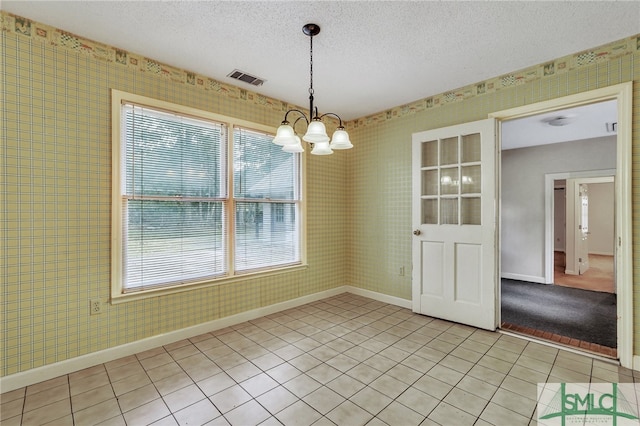 unfurnished dining area with light tile patterned floors, a textured ceiling, and an inviting chandelier