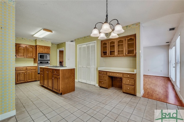 kitchen with a textured ceiling, a chandelier, pendant lighting, light hardwood / wood-style floors, and stainless steel appliances