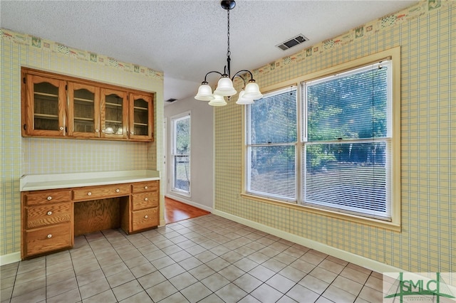 kitchen with light tile patterned flooring, a textured ceiling, an inviting chandelier, and hanging light fixtures