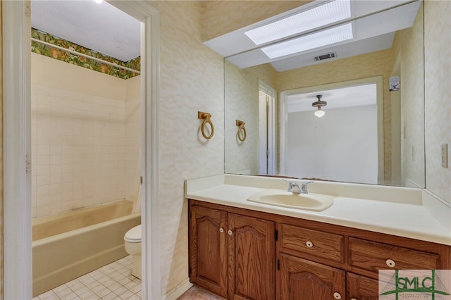 full bathroom featuring toilet, tiled shower / bath combo, vanity, and tile patterned flooring