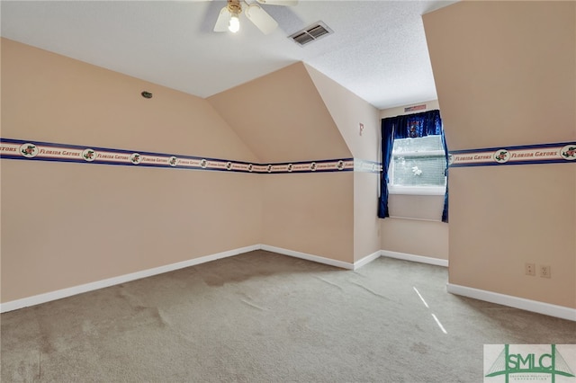 carpeted spare room featuring ceiling fan, a textured ceiling, and vaulted ceiling