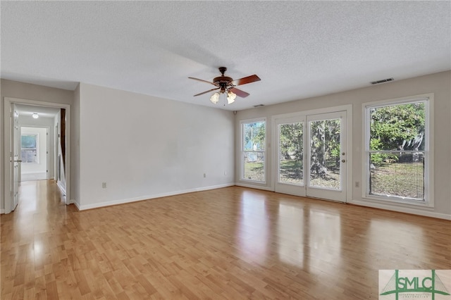 empty room featuring ceiling fan, a textured ceiling, and light hardwood / wood-style flooring