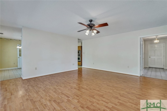 spare room featuring light hardwood / wood-style floors, a textured ceiling, and ceiling fan with notable chandelier