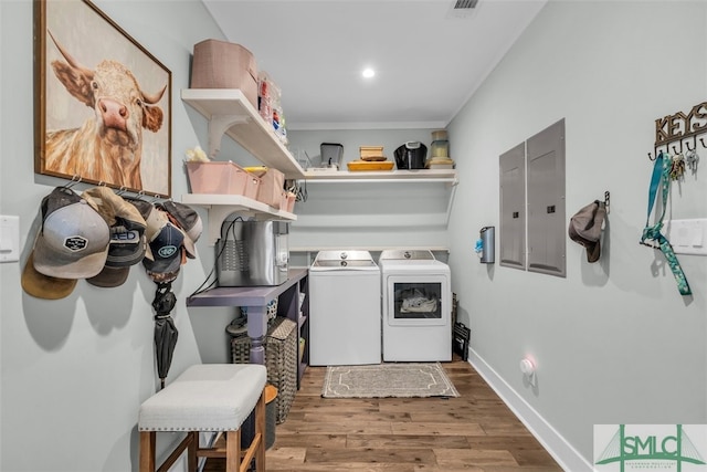 washroom featuring wood-type flooring, electric panel, and washing machine and clothes dryer