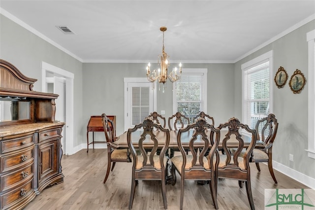 dining room featuring light hardwood / wood-style floors, crown molding, and an inviting chandelier