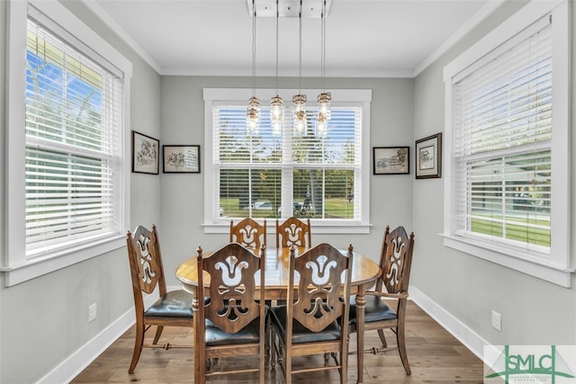 dining area with ornamental molding, a notable chandelier, hardwood / wood-style floors, and plenty of natural light