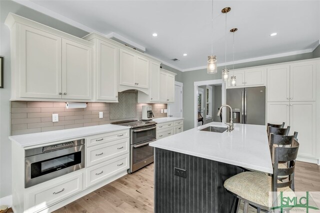 5261 Mill Branch Club Rd, Pembroke, GA 31321 - kitchen featuring stainless steel appliances, a sink, light wood-style floors, backsplash, and light countertops