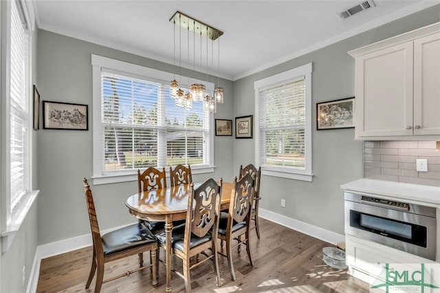 dining space featuring ornamental molding, light hardwood / wood-style flooring, and an inviting chandelier