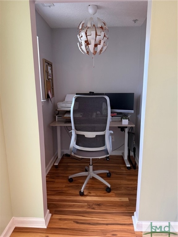 office area with a notable chandelier, hardwood / wood-style flooring, and a textured ceiling