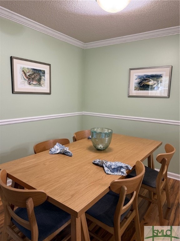 dining room featuring ornamental molding, a textured ceiling, and wood-type flooring