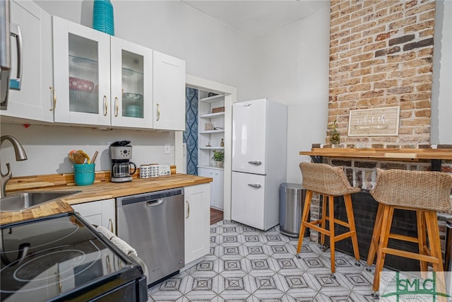 kitchen with butcher block counters, white cabinetry, sink, and stainless steel appliances