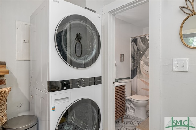 laundry room with electric panel and stacked washer and clothes dryer