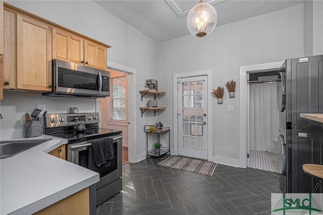 kitchen with light brown cabinets, stainless steel appliances, hanging light fixtures, and a healthy amount of sunlight