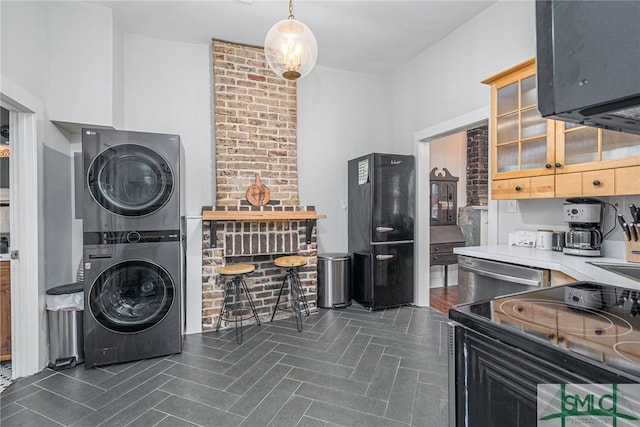 kitchen featuring pendant lighting, appliances with stainless steel finishes, and stacked washer and clothes dryer