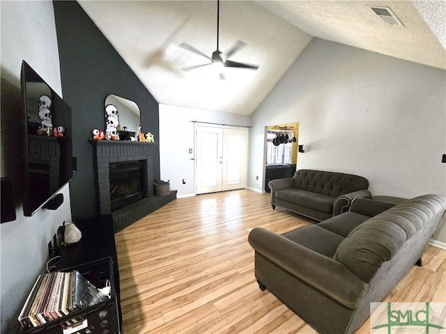 living room with high vaulted ceiling, a fireplace, light hardwood / wood-style floors, and ceiling fan