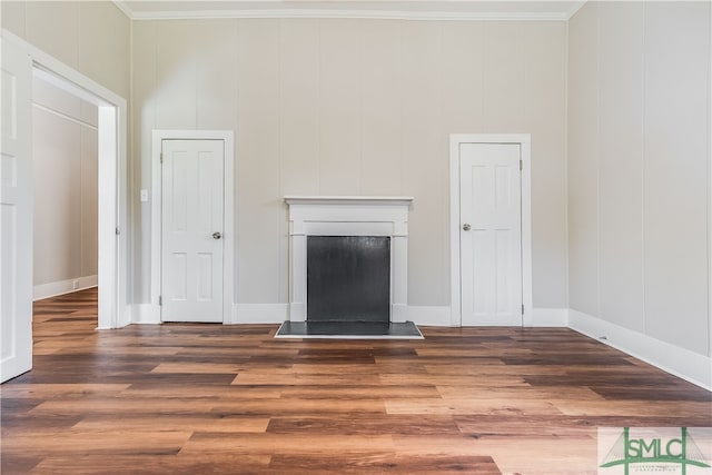 unfurnished living room with crown molding and dark wood-type flooring