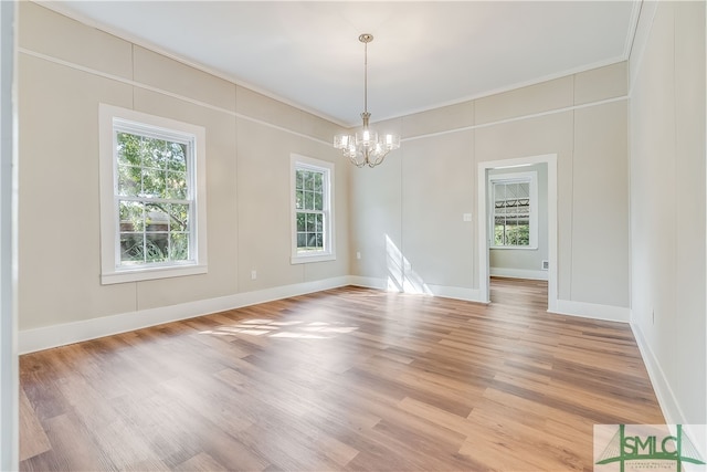 empty room with an inviting chandelier, light hardwood / wood-style flooring, and ornamental molding