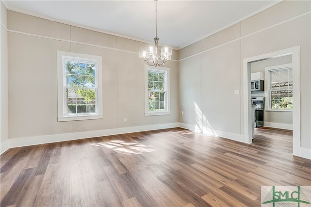 unfurnished dining area featuring an inviting chandelier, hardwood / wood-style floors, and ornamental molding