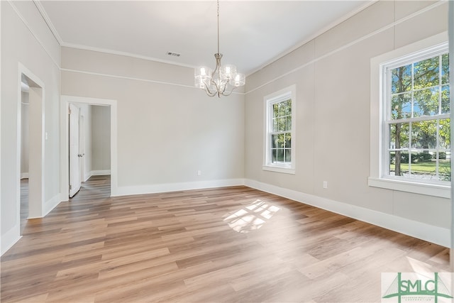 empty room with crown molding, an inviting chandelier, and light hardwood / wood-style floors