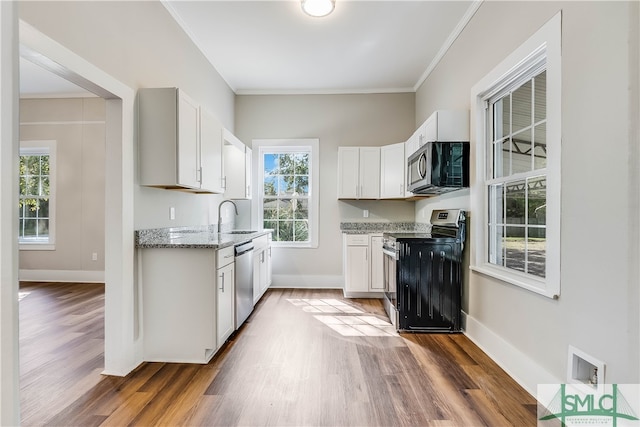 kitchen with crown molding, stainless steel appliances, light stone countertops, and white cabinets