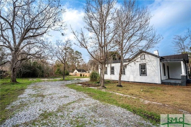 view of side of home with a yard and covered porch