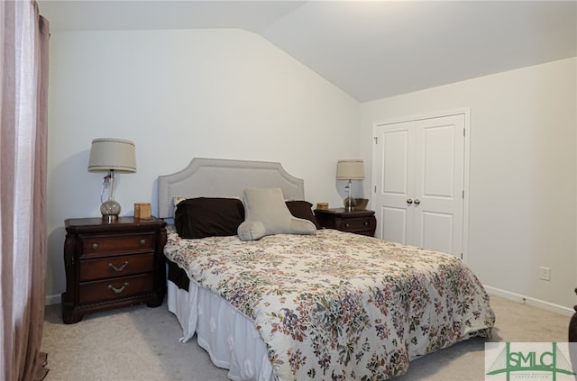 bedroom with a closet, lofted ceiling, and light colored carpet