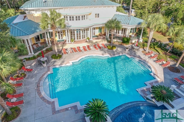 back of property with metal roof, a patio, a standing seam roof, and a community pool