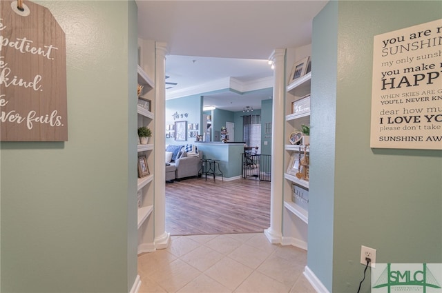 corridor featuring built in features, tile patterned flooring, crown molding, and baseboards