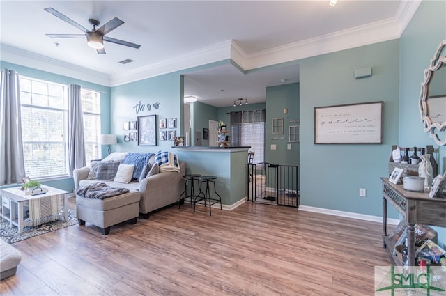 living room featuring baseboards, wood finished floors, visible vents, and crown molding