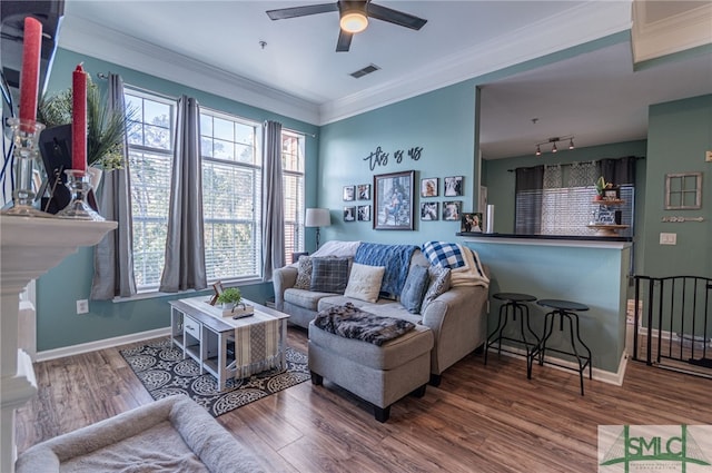 living room featuring baseboards, visible vents, crown molding, and wood finished floors