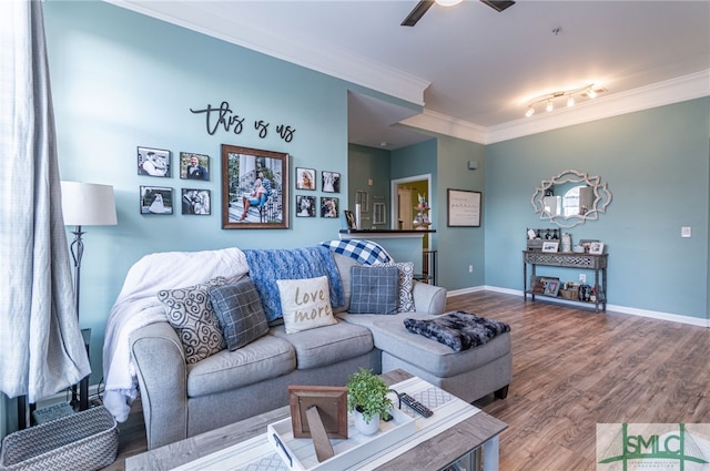 living area featuring a ceiling fan, crown molding, baseboards, and wood finished floors