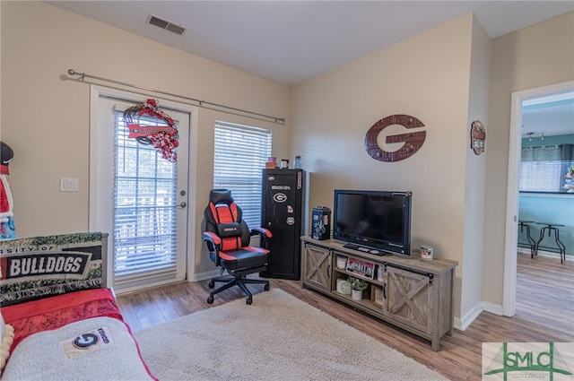 living area with baseboards, visible vents, a wealth of natural light, and wood finished floors