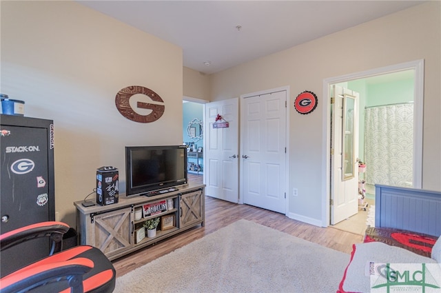 bedroom featuring wood finished floors, connected bathroom, and baseboards