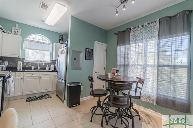 kitchen with dark countertops, white cabinets, backsplash, and freestanding refrigerator