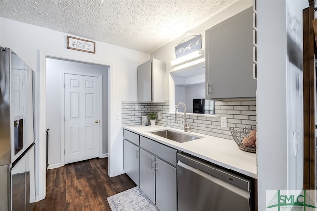 kitchen featuring dark wood-type flooring, gray cabinetry, sink, appliances with stainless steel finishes, and a textured ceiling