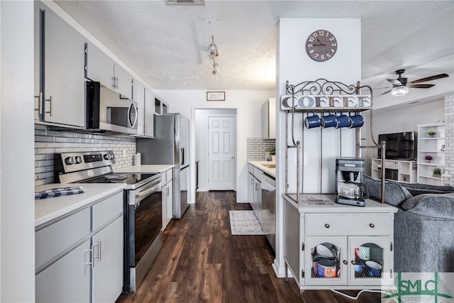 kitchen featuring dark wood-type flooring, appliances with stainless steel finishes, a textured ceiling, and ceiling fan