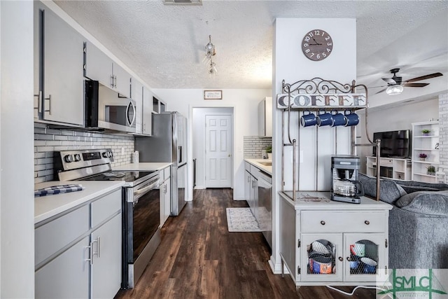 kitchen with dark hardwood / wood-style floors, stainless steel appliances, backsplash, and a textured ceiling